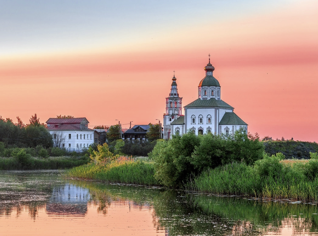 Scenic view of the Kamenka River in Suzdal, with historic churches, traditional houses, and green riverbanks