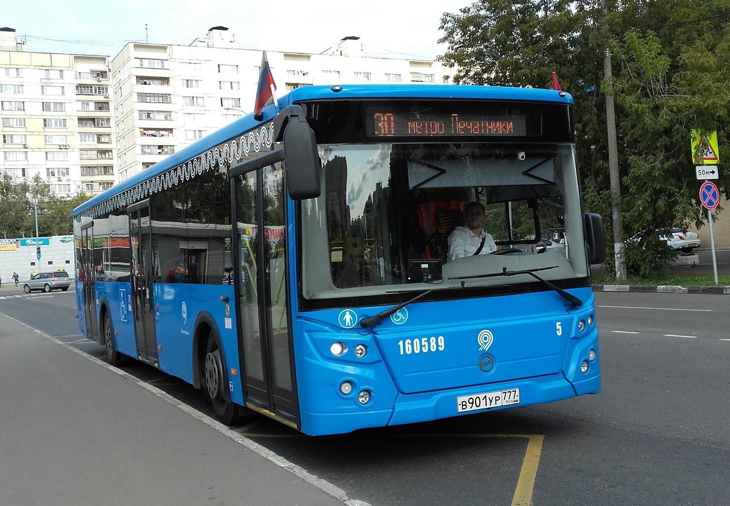 Blue city bus traveling along a street in Moscow, Russia